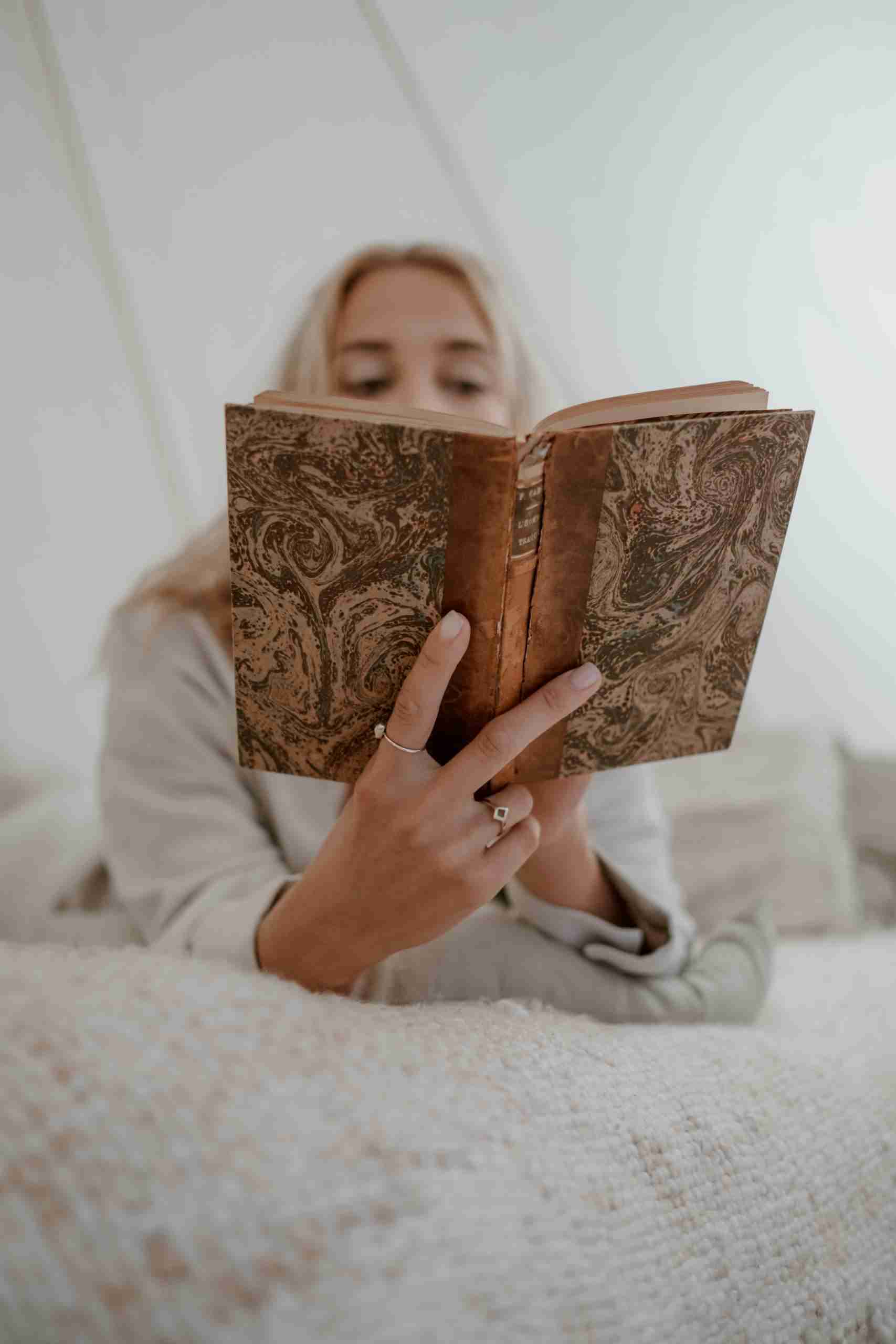 A woman reading a vintage book in a cozy, softly lit indoor setting, creating a serene and contemplative mood.