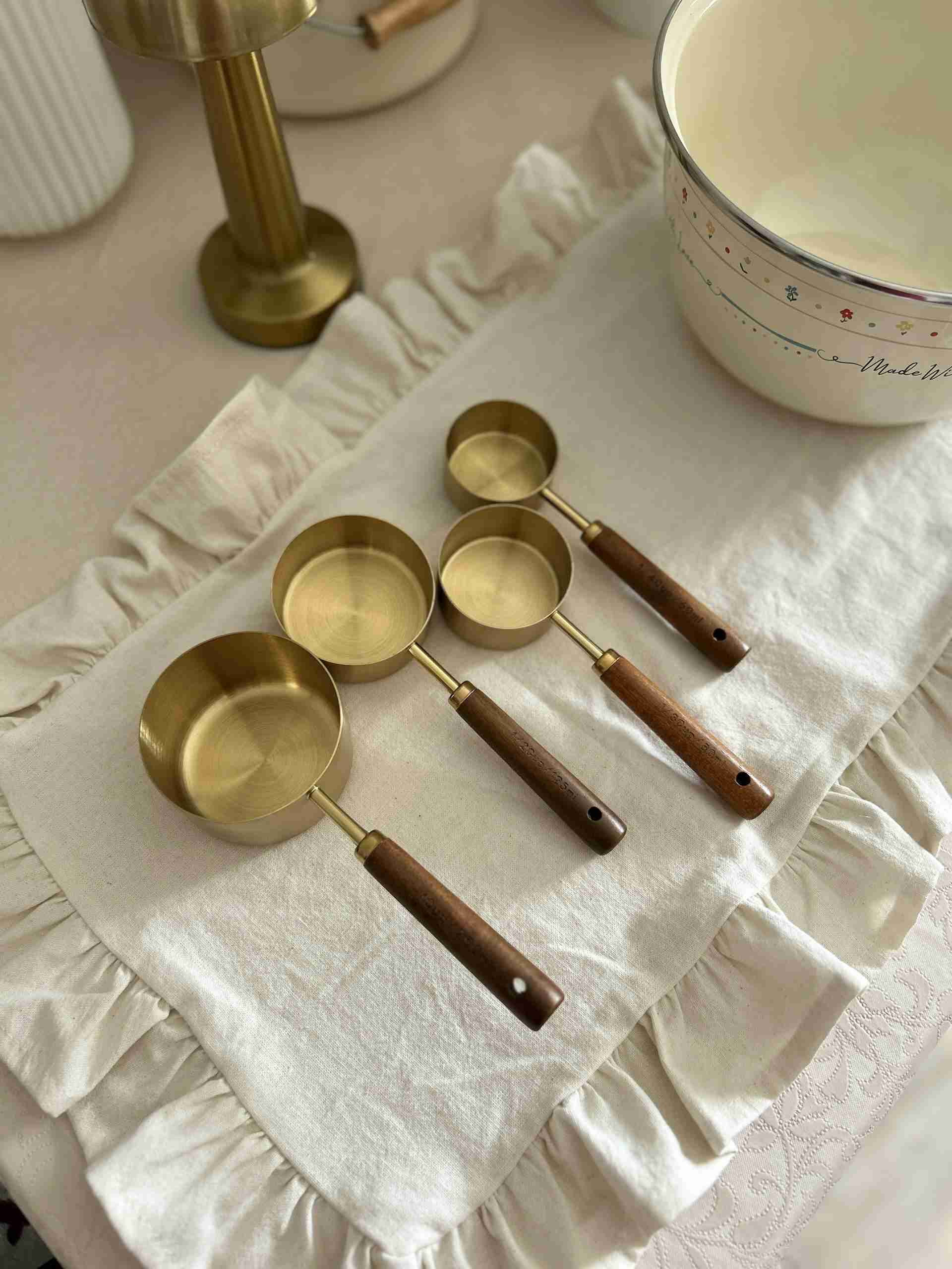 Beautifully arranged brass measuring cups on a rustic kitchen fabric.