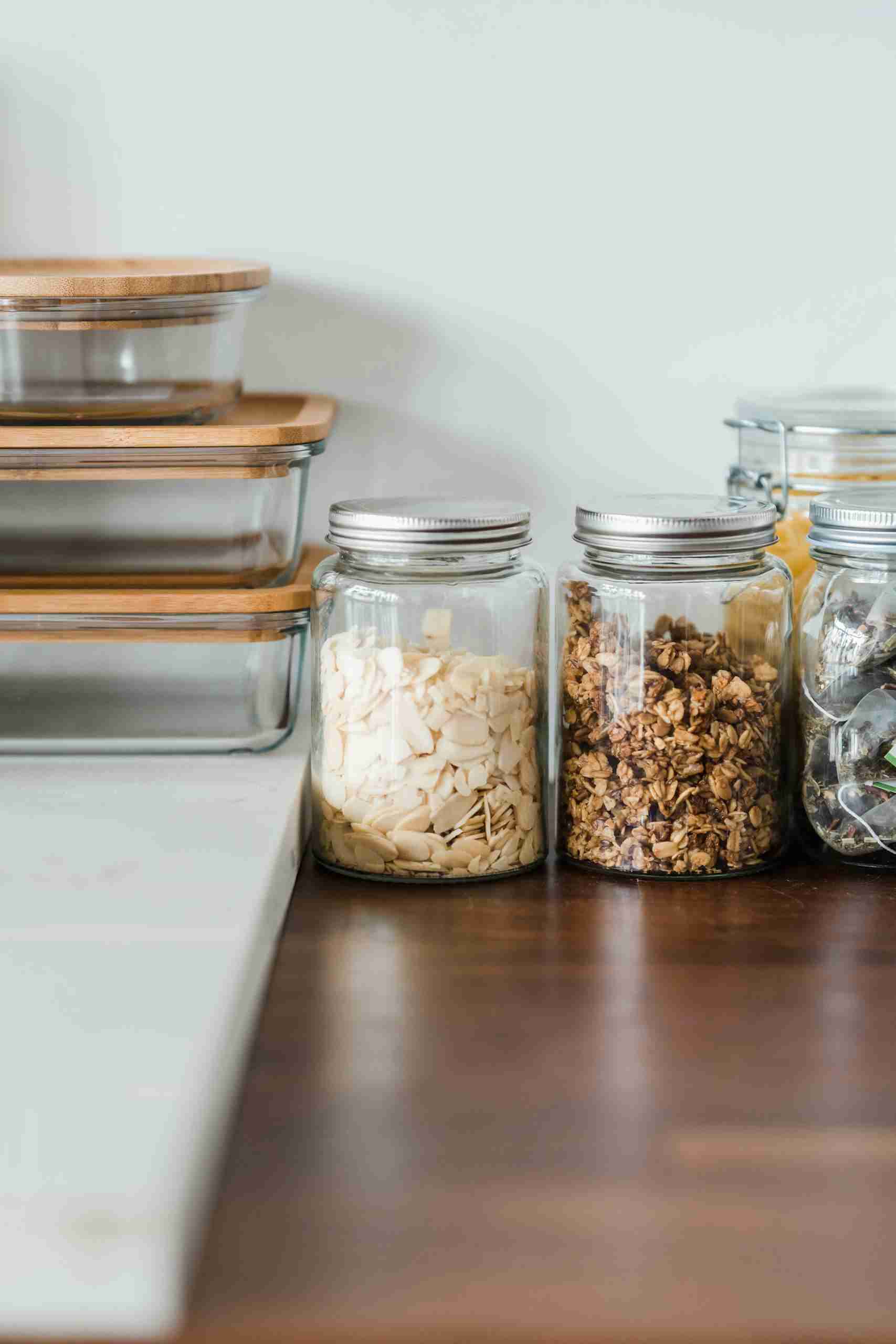 Neat kitchen setup with glass jars filled with snacks and food storage containers on a wooden counter.